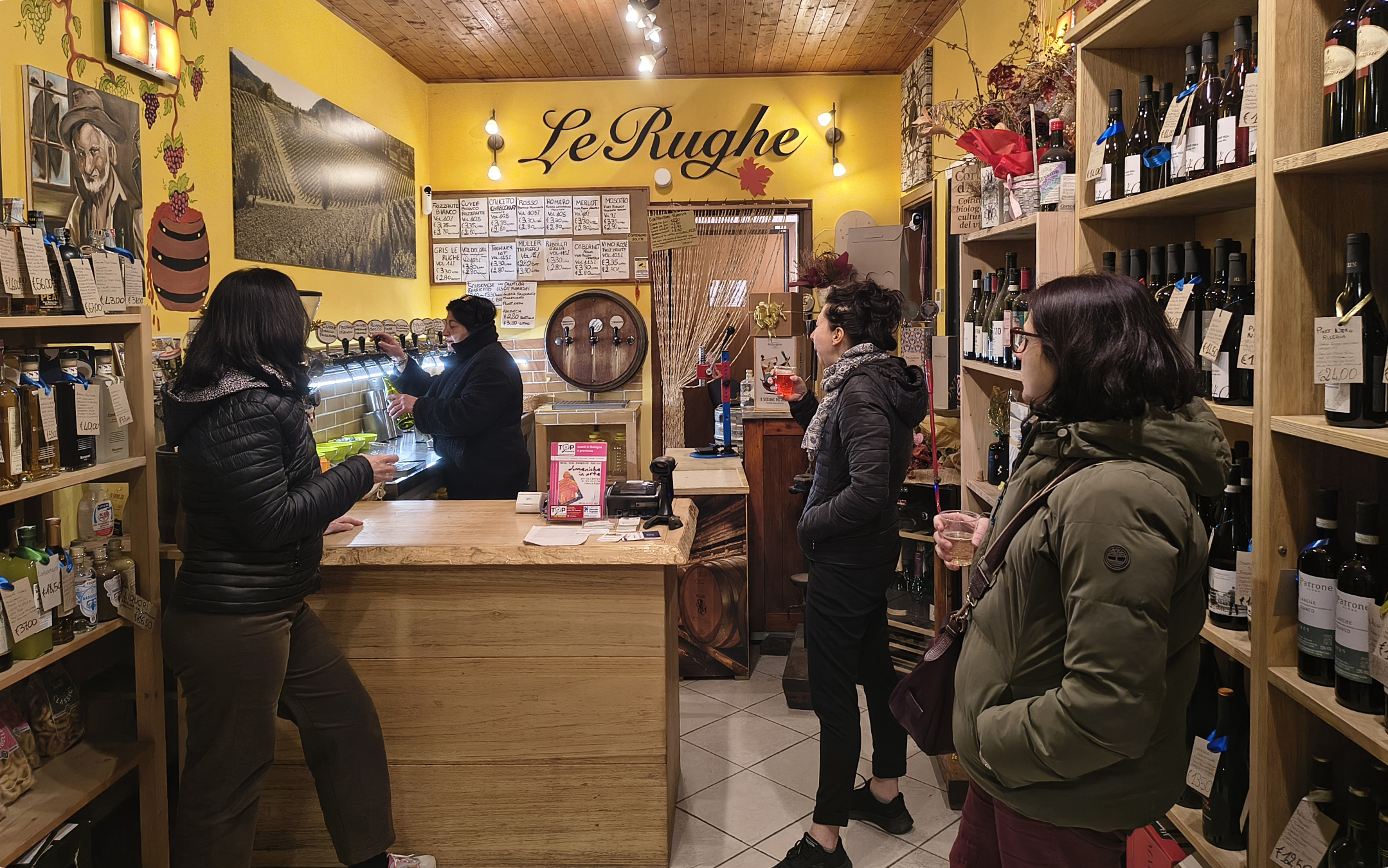 Segnaposto: titolare con clienti mentre serve vino sfuso in enoteca